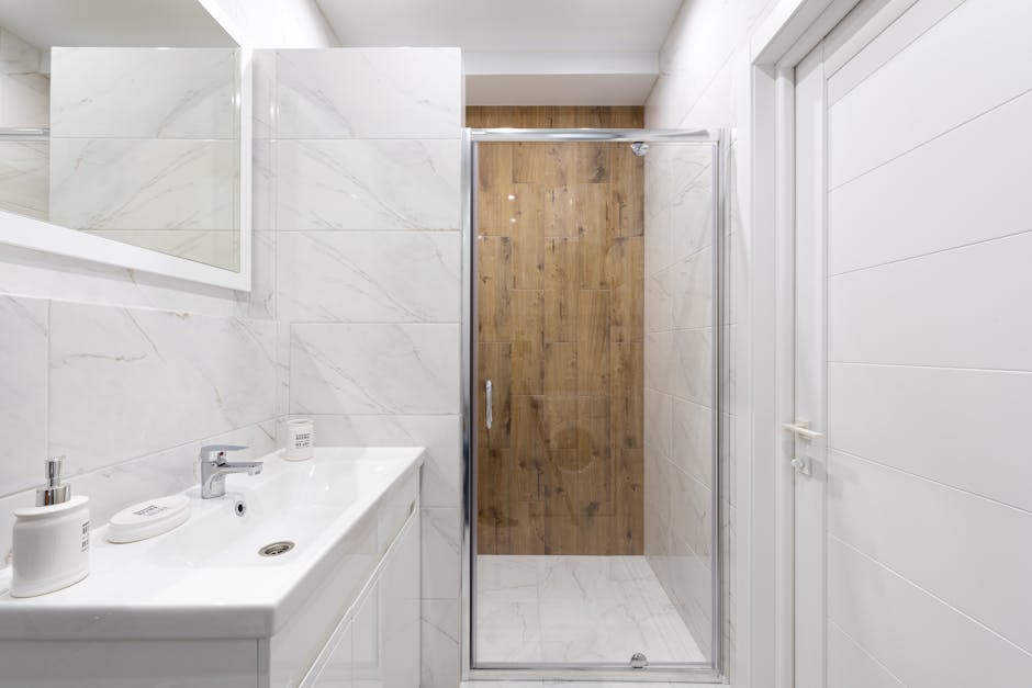 Modern bathroom with washstand under rectangular mirror on tiled wall against shower room in light house