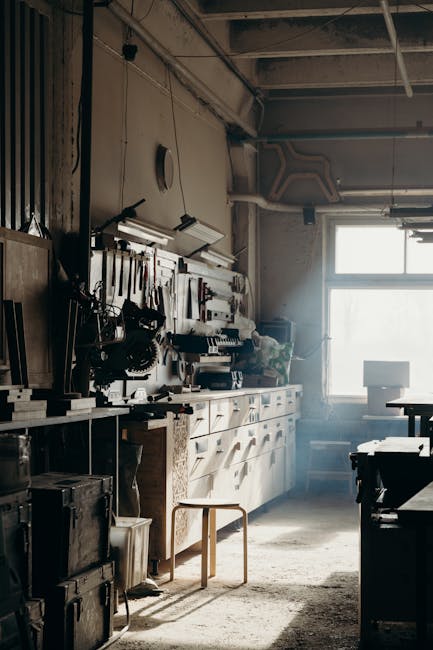 Sunlight streaming through a window in a vintage workshop filled with tools and wooden furniture.