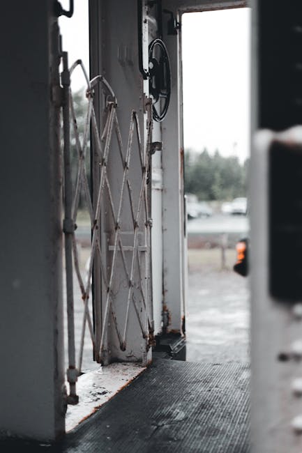 An outdoor view through a rusty metal gate, capturing an industrial atmosphere.