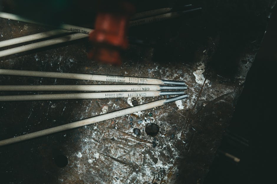 Close-up of welding electrodes on a rugged metal surface, showcasing industrial tools.
