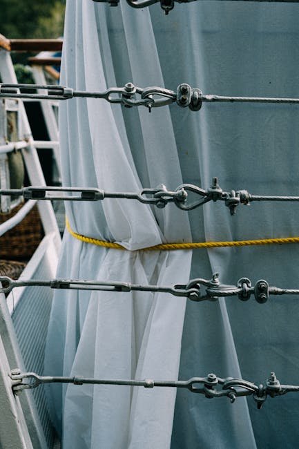 Detailed view of metal turnbuckles and ropes on a ship with white cloth background, showcasing marine equipment.